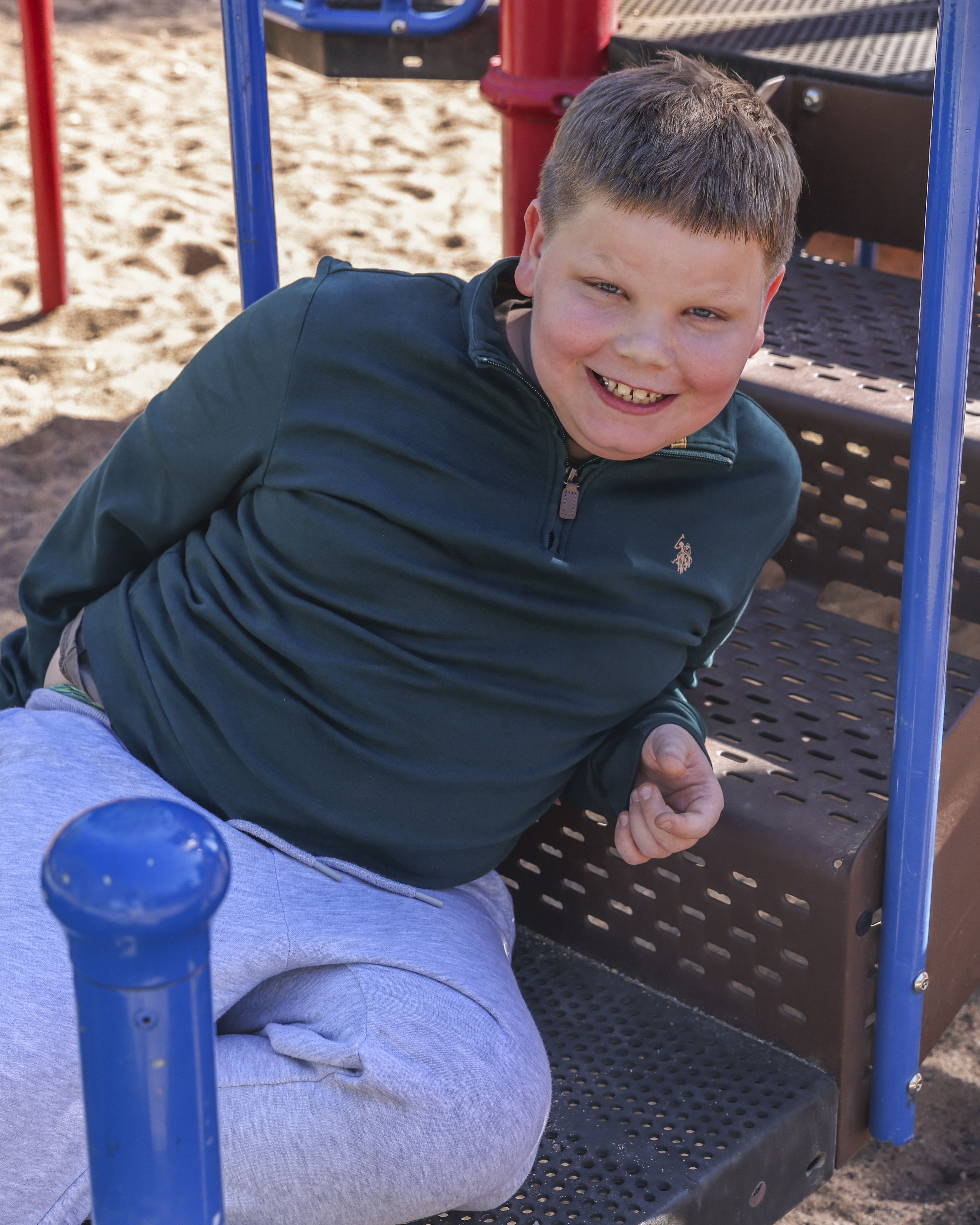 Allen leaning on playground equipment smiling