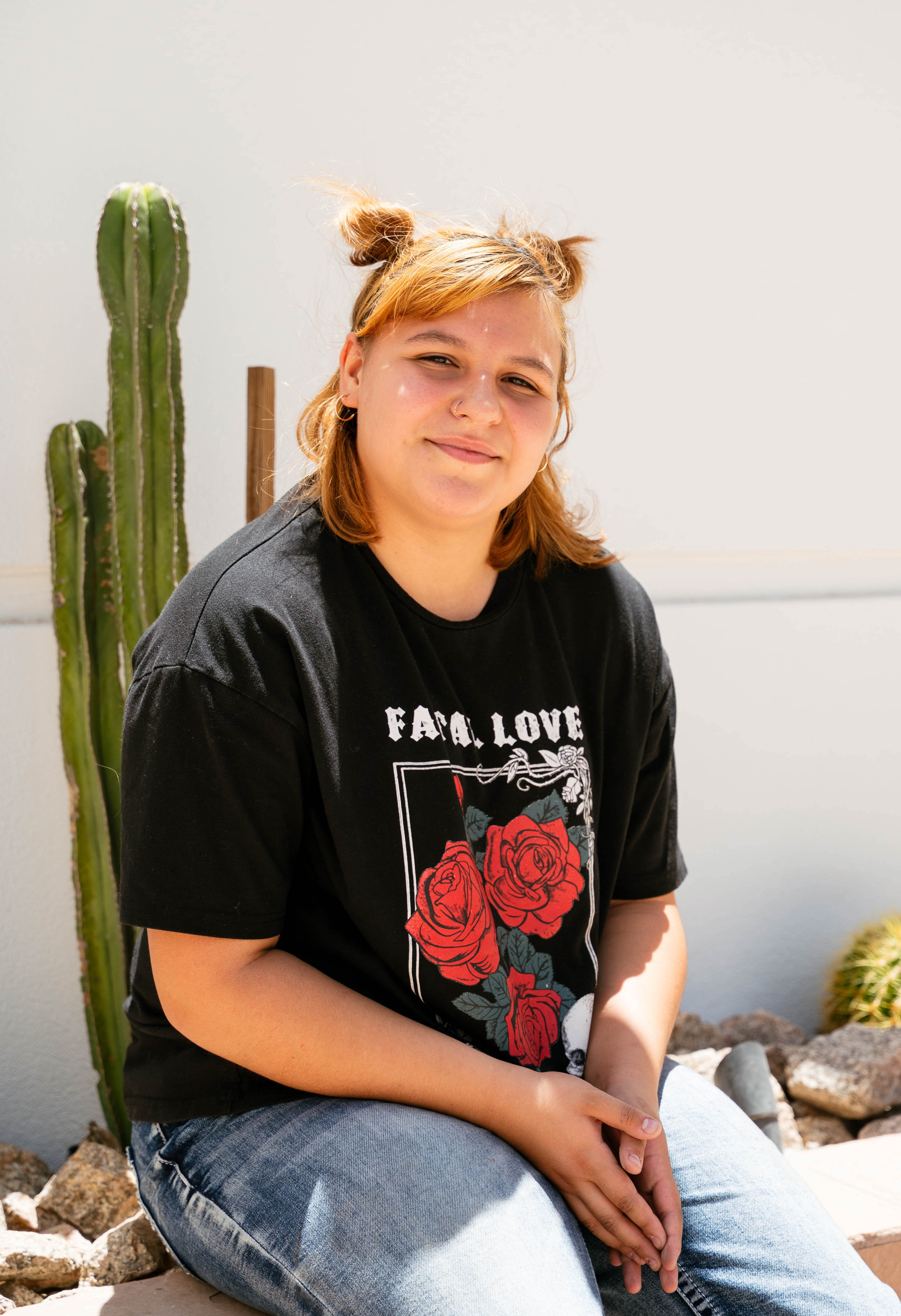 Valeria sitting on wall with cactus in background