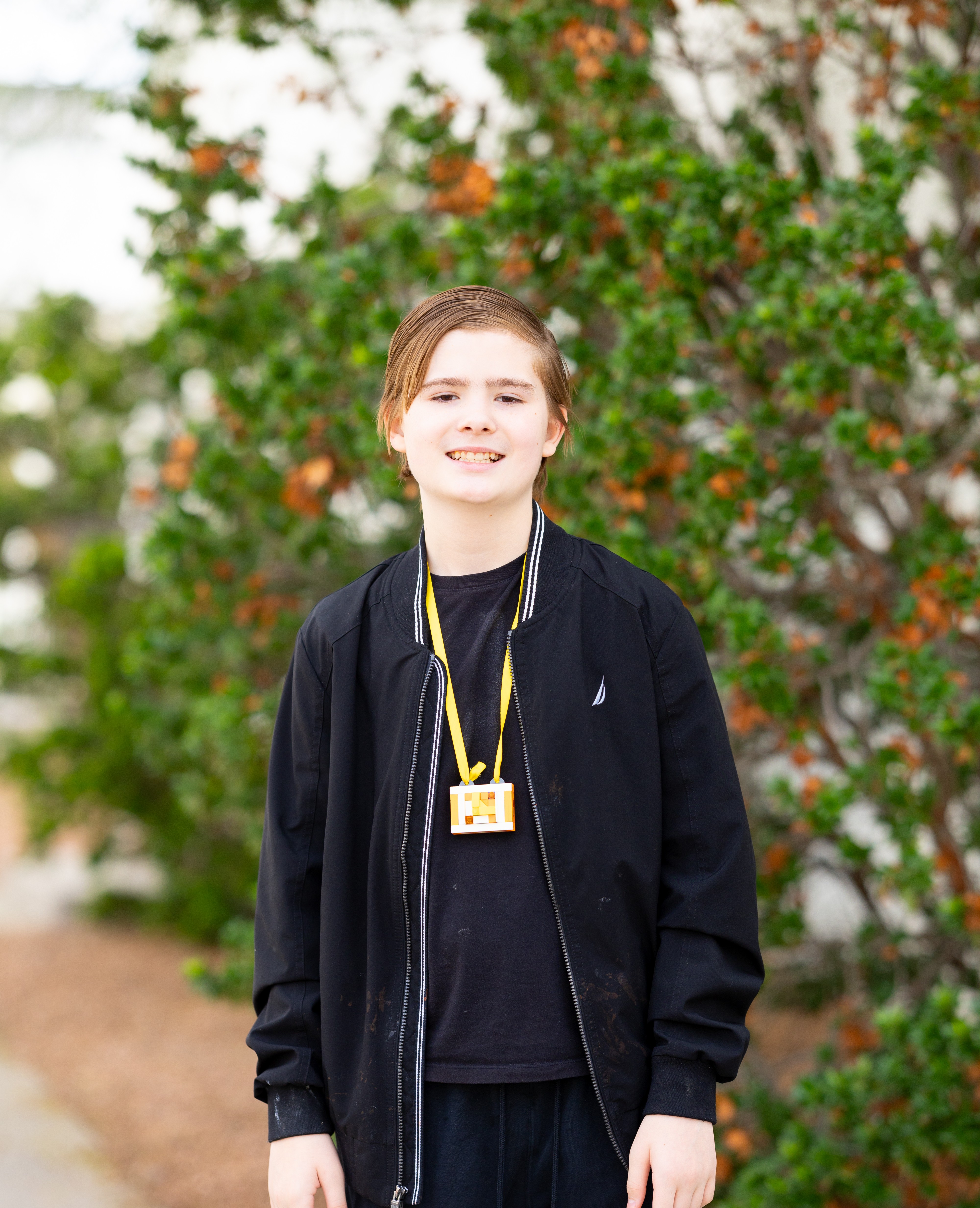 Ethan standing in black with bush in background