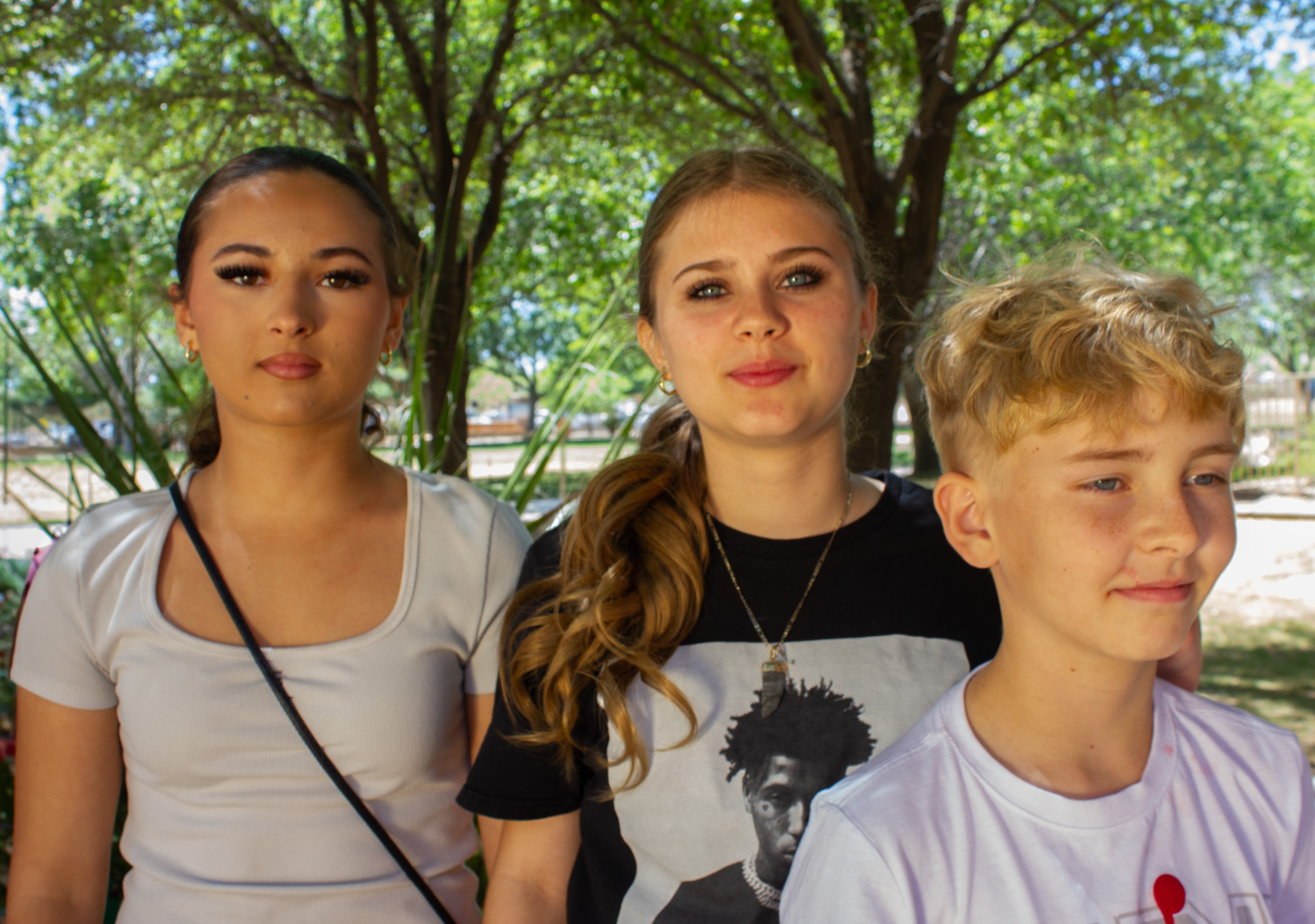Amiya, Mayra, and Wyatt standing under trees