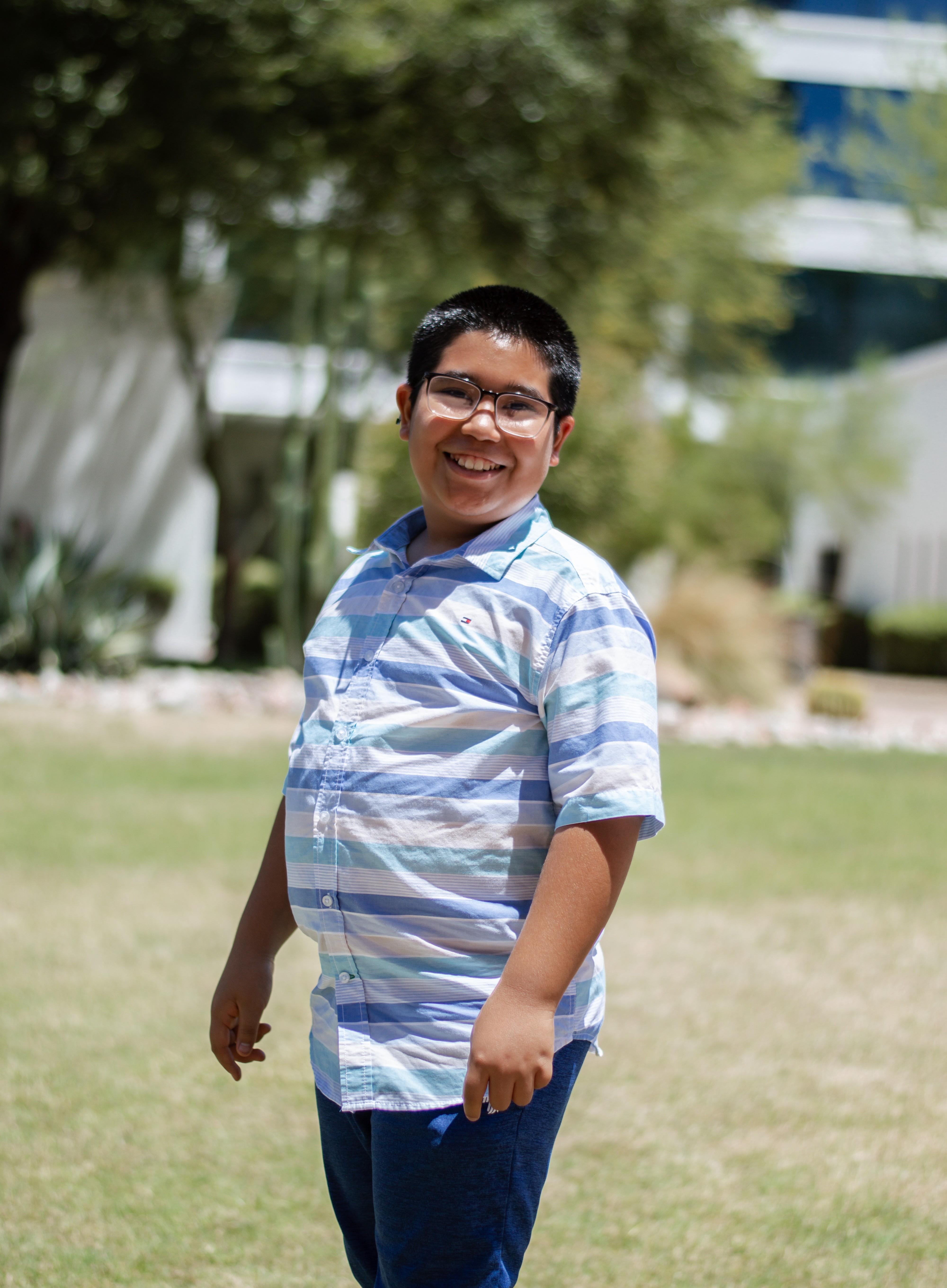 Reyes standing sideways in grass with tree in background