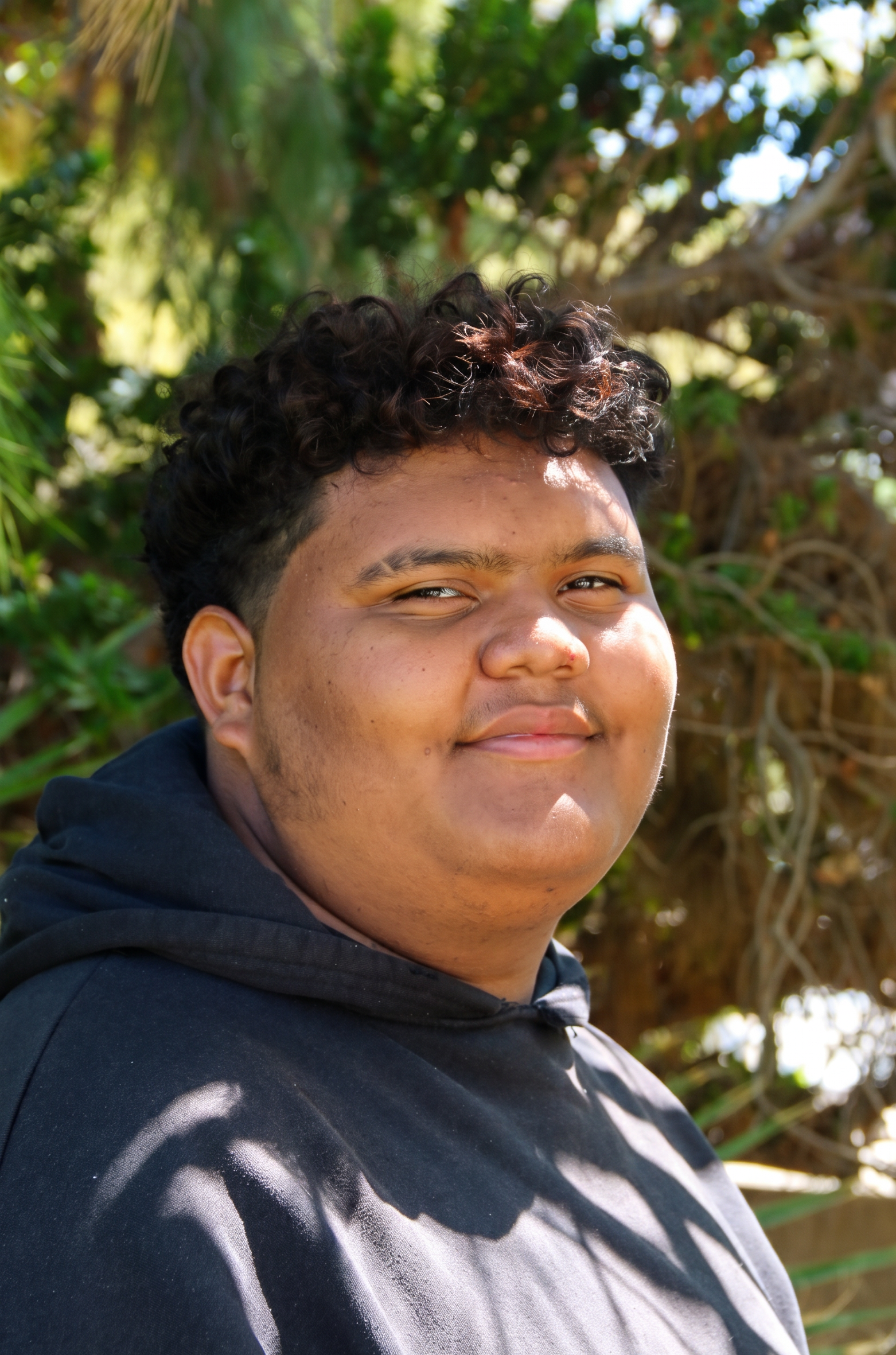 Brayan smiling with trees in background