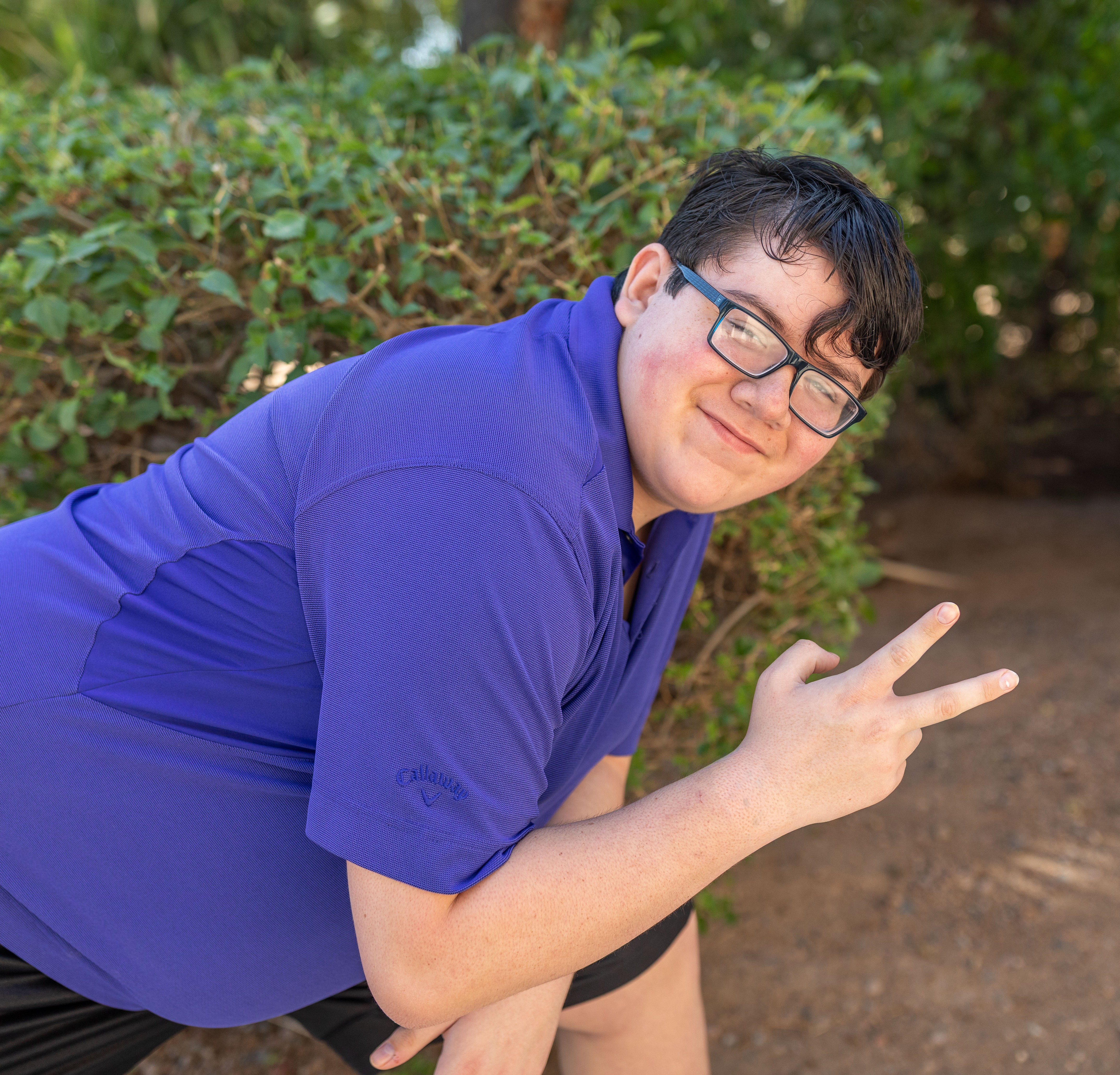 Elijah bending down smiling with peace sign