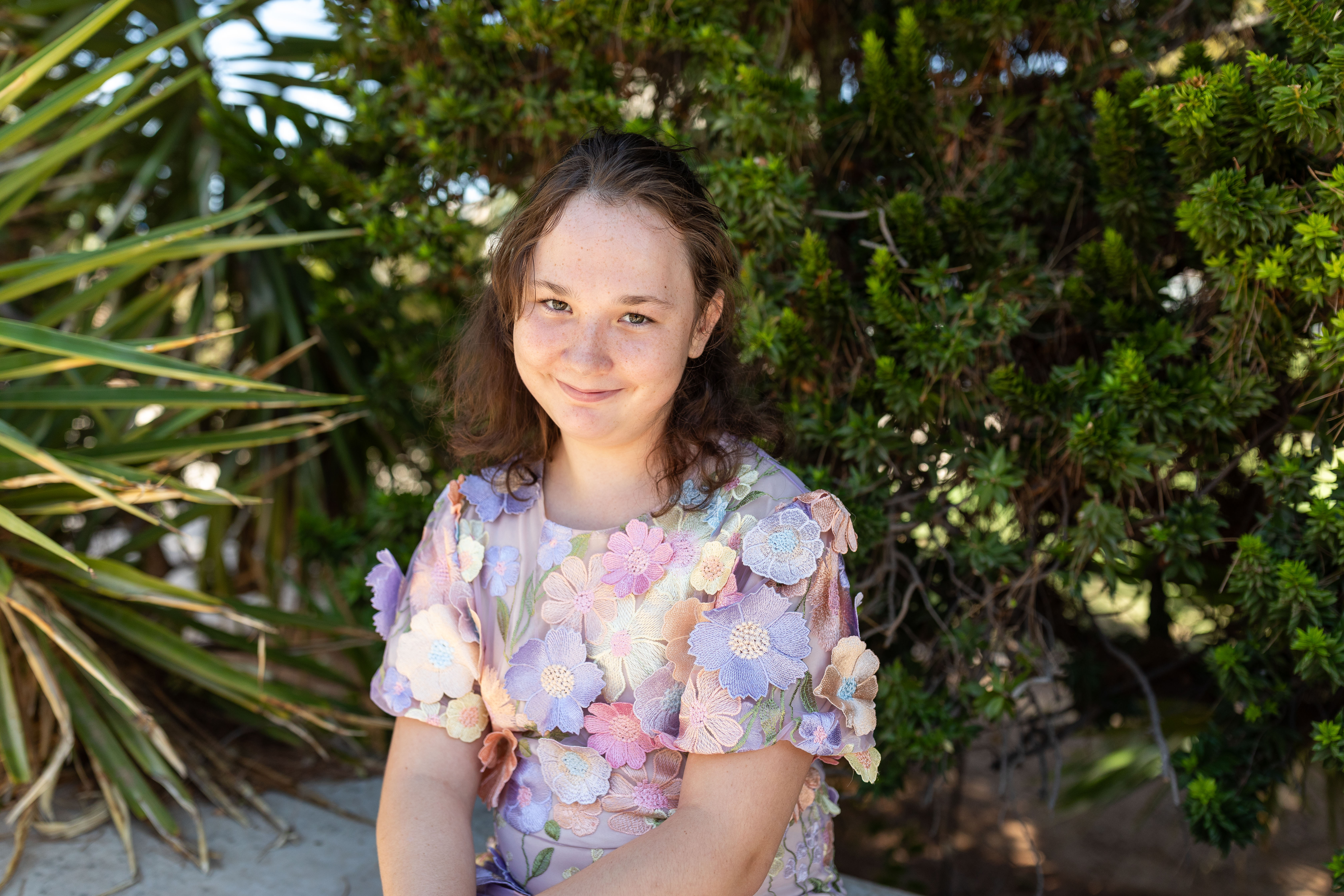 Grace sitting with bushes in the background