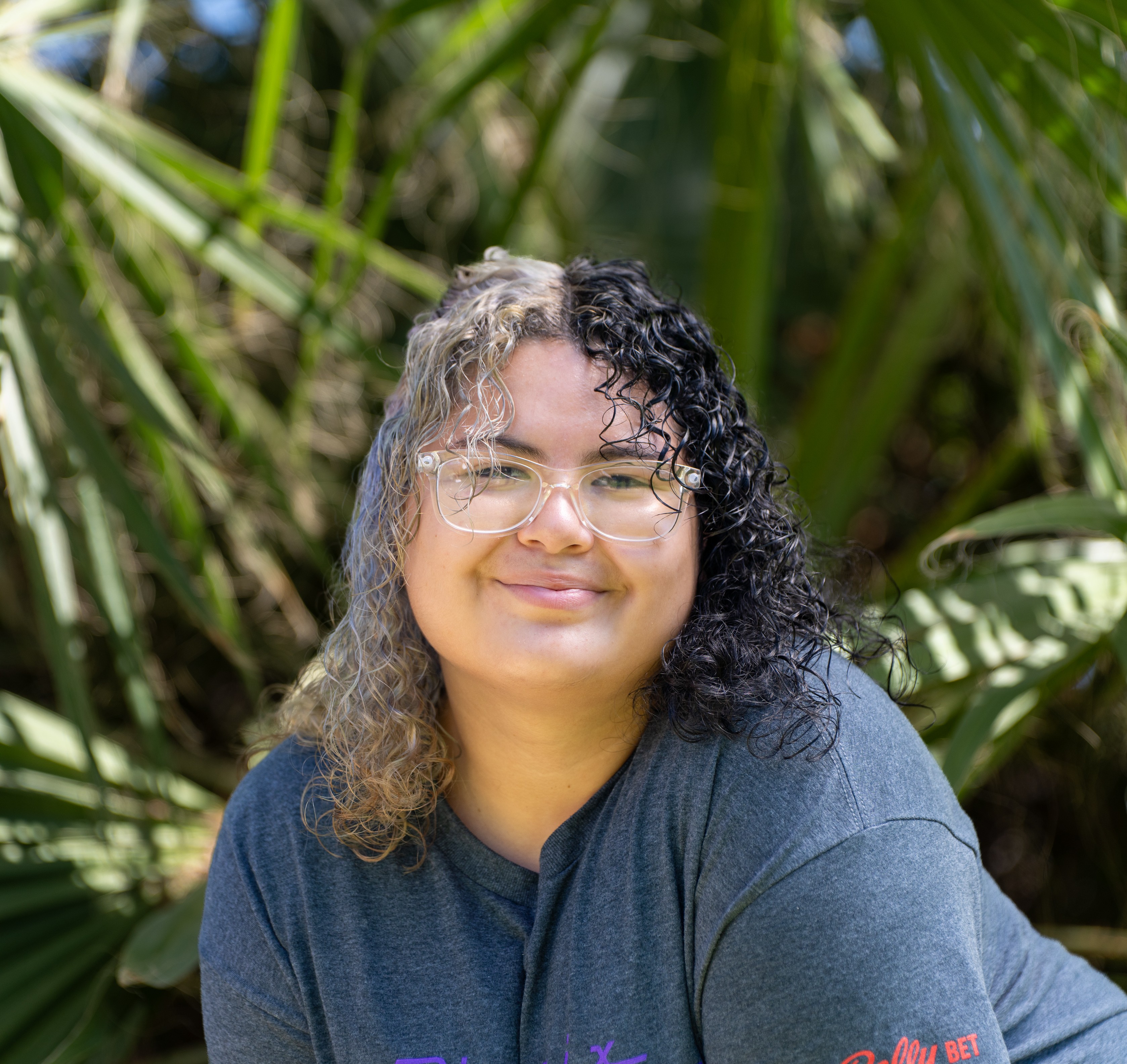 Shenelle bending smiling with palm trees in background
