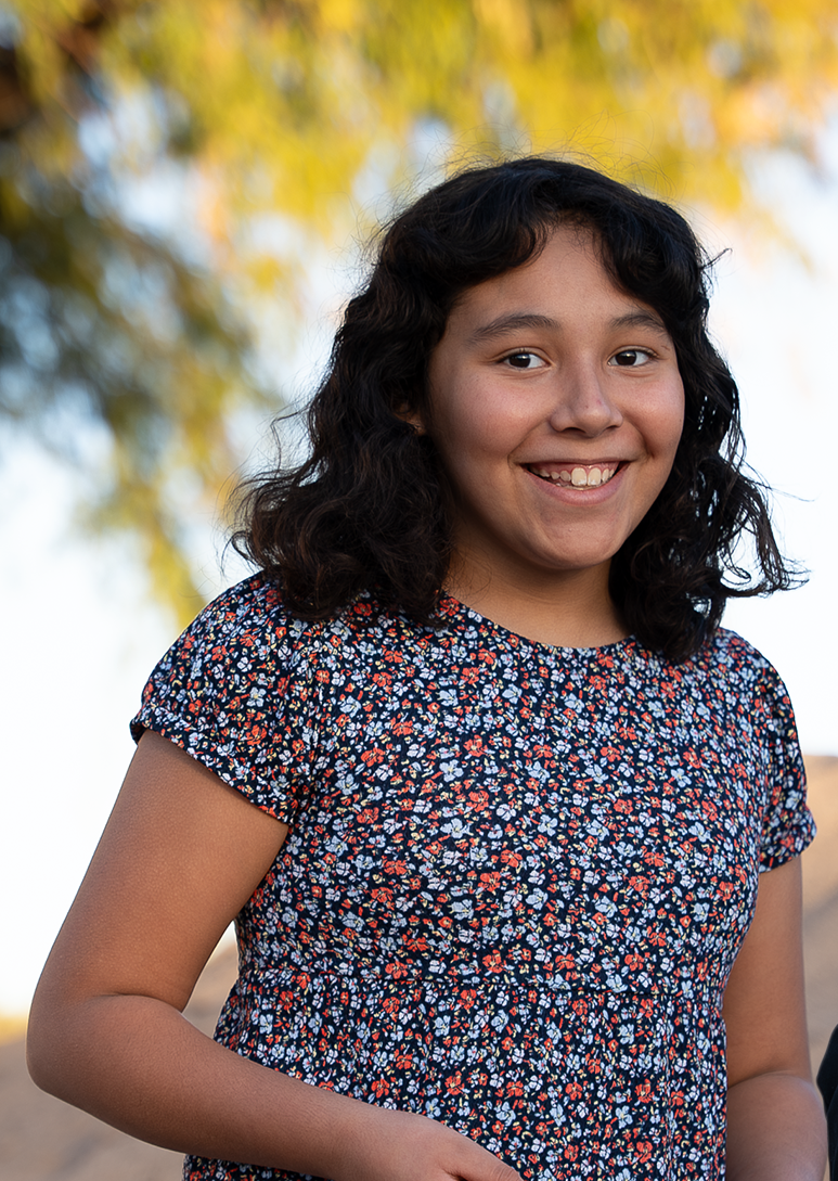 Adrianna standing smiling with tree in background