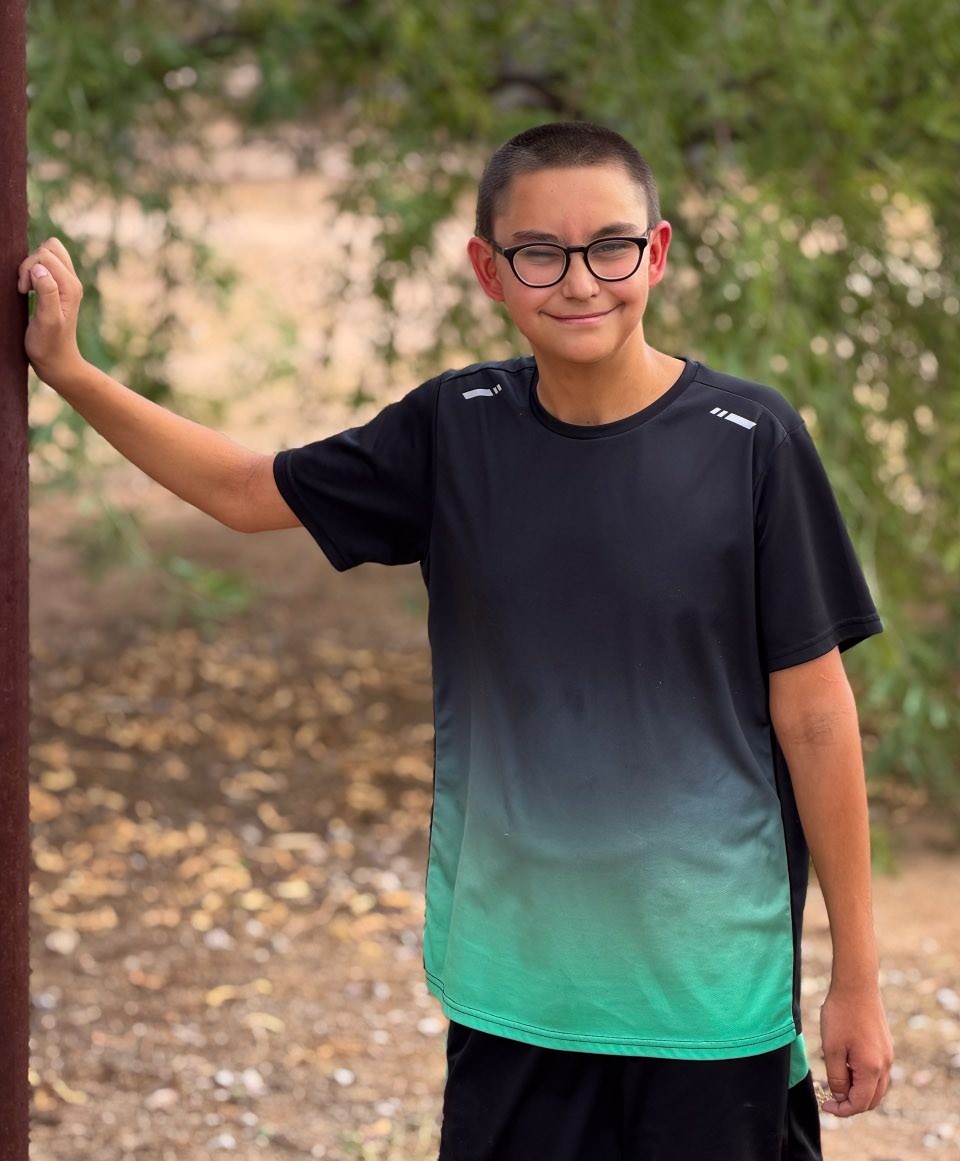 Jacob leaning on a wall with tree in background