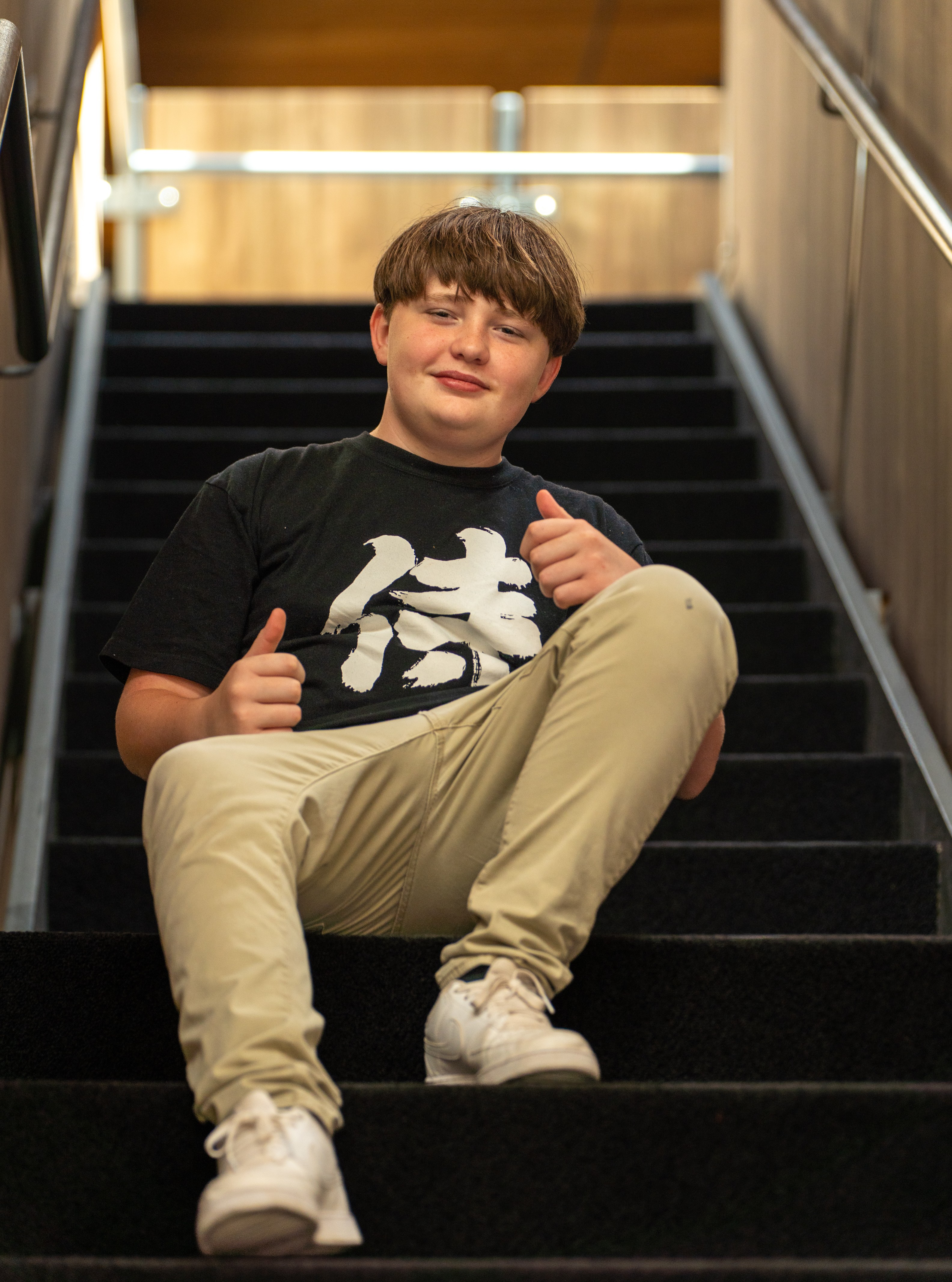 Jaxon sitting on stairs with thumbs up