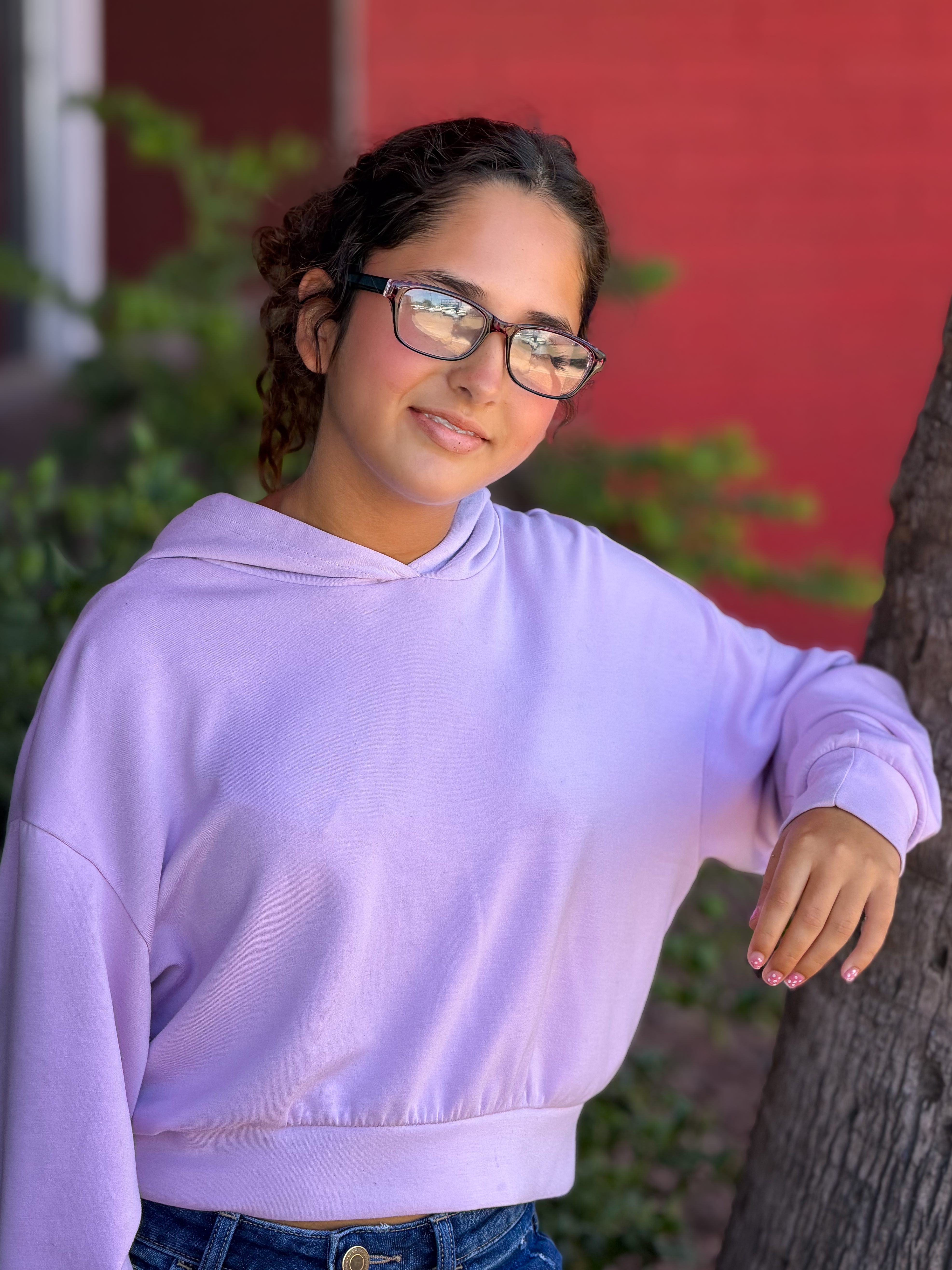 Cecilia standing leaning on a tree