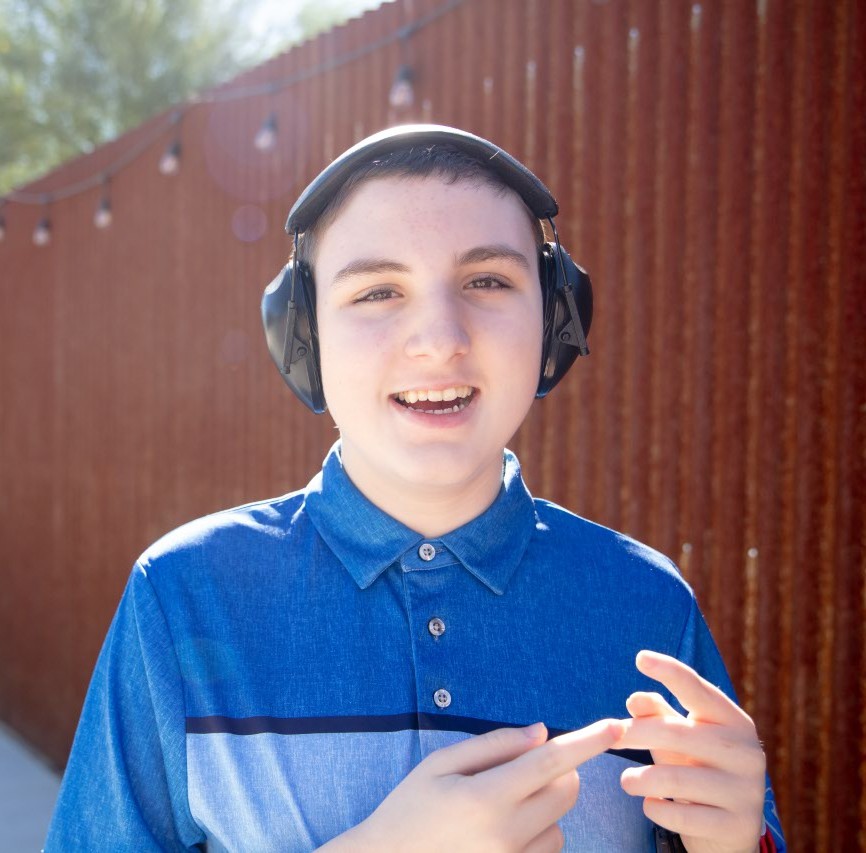 Gage smiling with brown wall in background 
