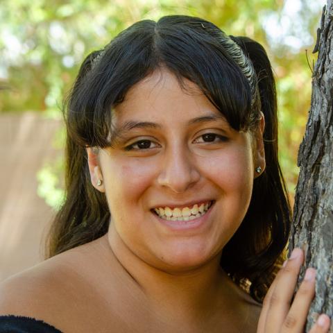 Destiny smiling leaning on a tree.