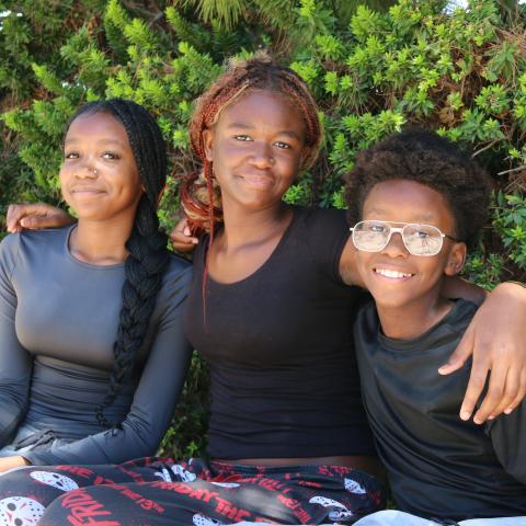 Lillian, Carla and Carlo sitting in front of bushes 