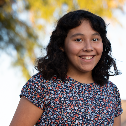 Adrianna standing smiling with tree in background