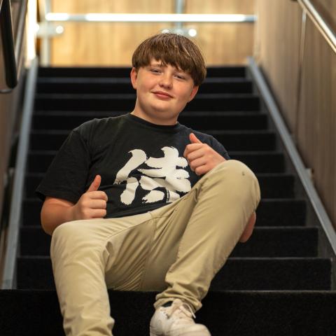 Jaxon sitting on stairs with thumbs up